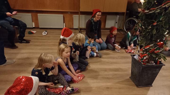 Spejdere med nissehuer sidder på gulvet med pakker foran sig og et fjollet juletræ lavet af en stuebirk